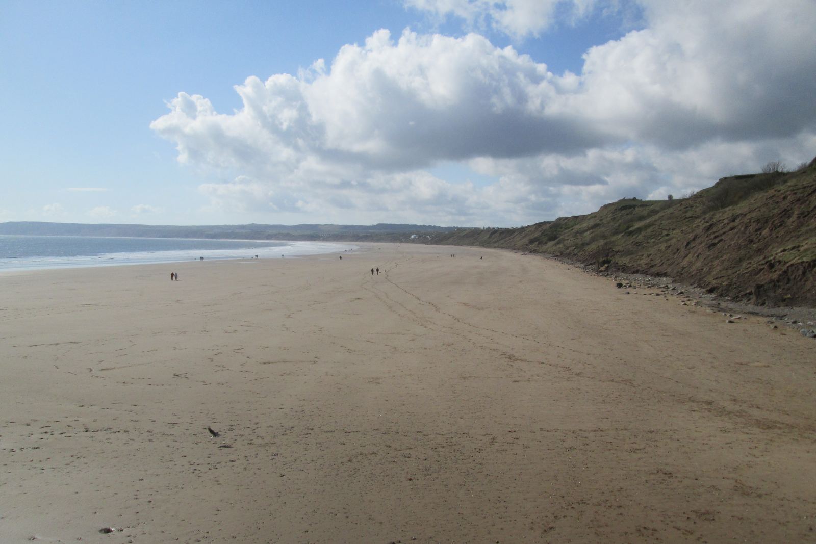 Wide, empty Filey Sands stretching south toward Muston Sands beneath big white clouds and a blue sky